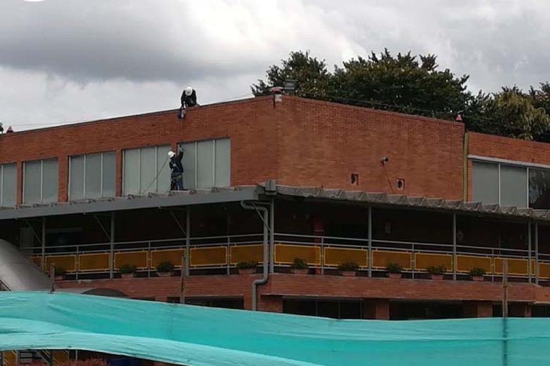 Fachada de ladrillo con operario en la cubierta en Chía